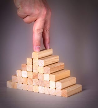 Male hand with two fingers on top of a wooden peg on a ladder