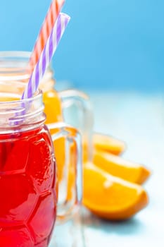 two cups with orange juice and strawberries on blue background