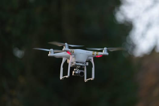 9 - Drone quadcopter with camera hovering in front of trees. Application in industrial inspection and surveillance too.