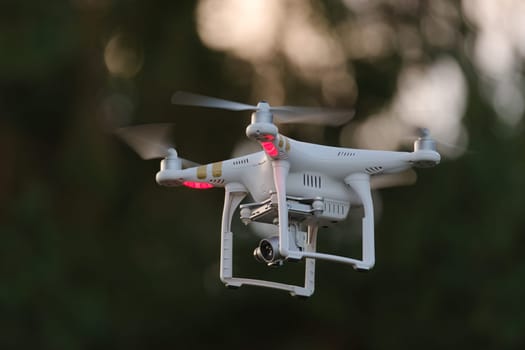 14 - White drone carrying a camera on a gimbal looks left. Plenty of copy space due to selective focus and dark background.