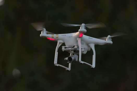 20 - Isolated quadcopter camera drone carrying digital camera. Plain dark background with selective focus, leaving the bright white drone as subject.