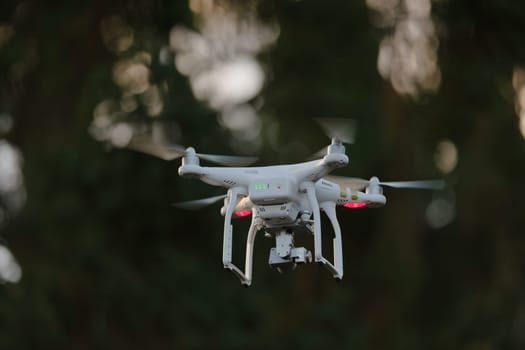 22 - Rear view of white quadcopter camera drone with gimbal underneath. Battery indicator lights show battery status on the back side of the aircraft