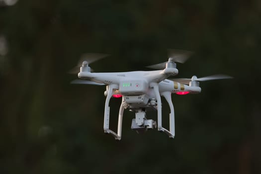 24 - White quadcopter surveillance video drone with dark background. Isolated subject using selective focus also stands out due to light color.