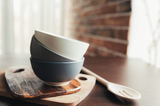 Three ceramic bowls, wooden spoon on a wooden brown table. Blurred background. High quality photo