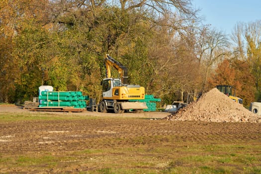Construction site in Magdeburg city park with excavator and sewage pipes