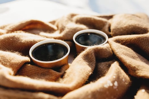 Two cups of coffee on a scarf in the snowy forest. High quality photo
