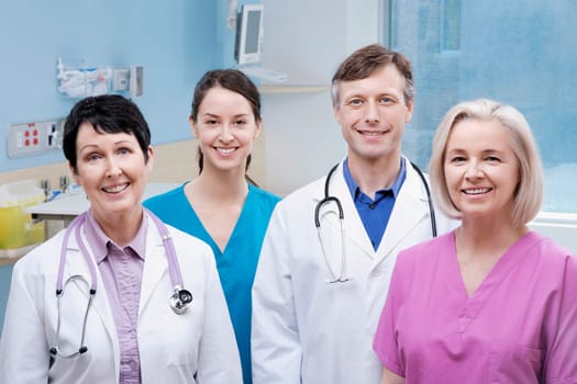 Two doctors standing with two nurses and smiling