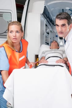 Paramedics leading a patient on a gurney from an ambulance