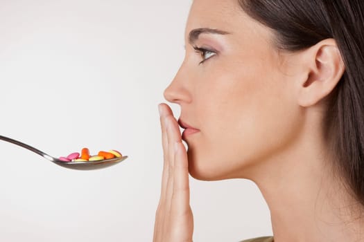 Close_up of a woman with a spoonful of pills