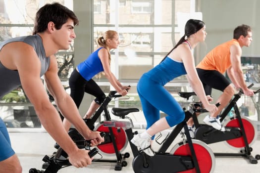Men and women working out on exercise bikes in a gym
