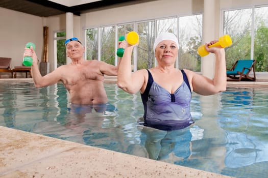 Couple exercising with dumbbells in a swimming pool