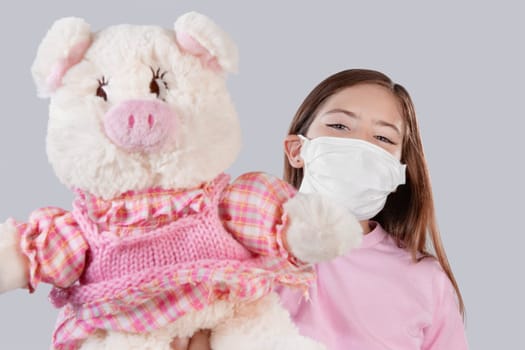 Girl wearing flu mask and showing a stuffed toy