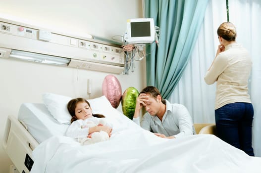 Girl on a hospital bed with her parents beside her