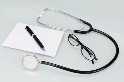 Close_up of a stethoscope with pen and prescription pad