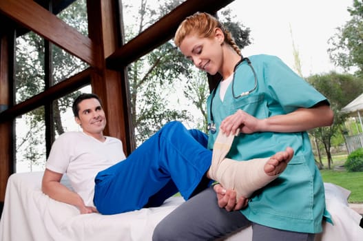 Female nurse rolling crepe bandage on a manŽs foot