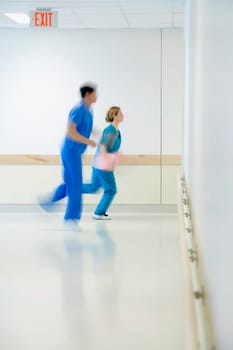 Two doctors running in a hospital corridor