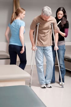Physiotherapist assisting a patient in walking with crutches