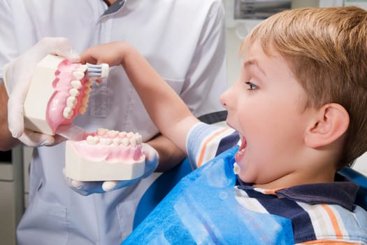 Boy learning how to brush teeth with the help of dentures in a dentistŽs office