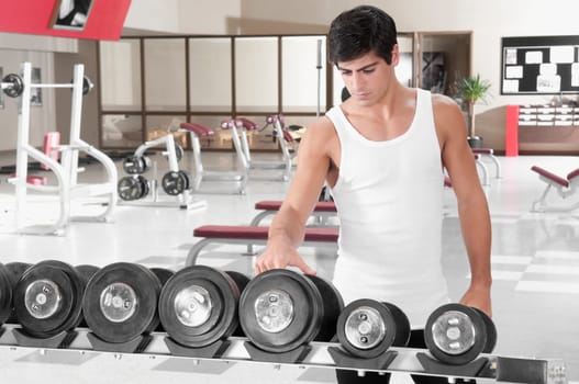 Man choosing dumbbells in a gym