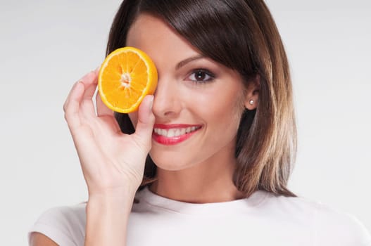 Woman holding an orange half over her eye