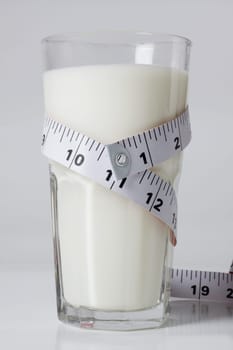 Close_up of a tape measure around a glass of milk