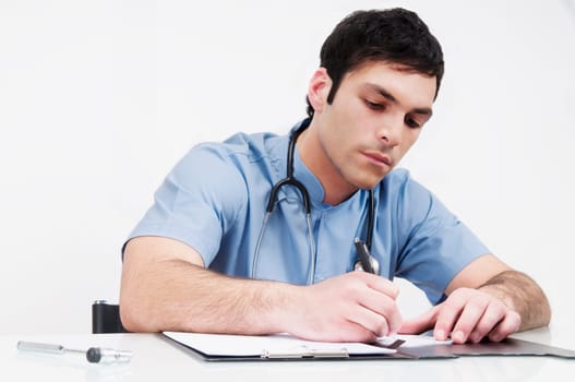 Doctor sitting at a table and writing in a file