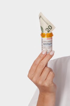 Doctor holding a pill bottle with a twenty currency note in it