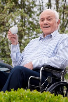 Portrait of a man sitting in a wheelchair and drinking tea