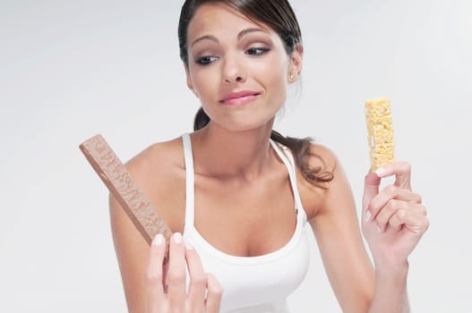 Woman choosing between a chocolate and a protein bar