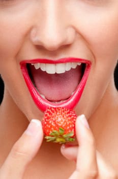 Close_up of a woman putting a strawberry in her mouth