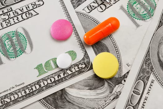 Close_up of pills on hundred dollar bills