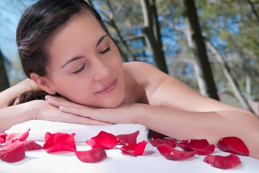 Woman lying on a massage table with rose petals in front of her