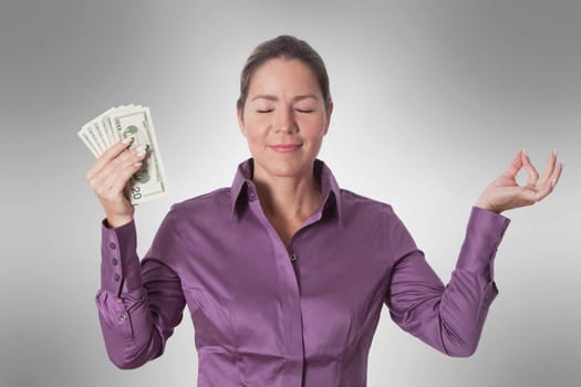 Woman meditating and holding currency notes