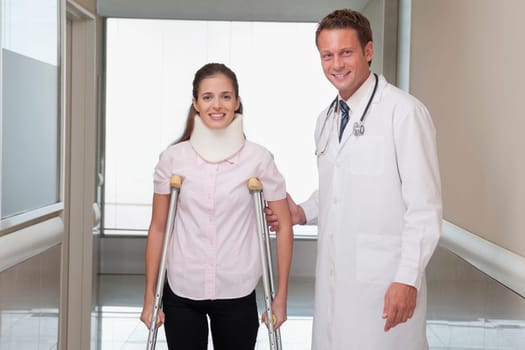 Doctor assisting a patient to walk in a hospital corridor