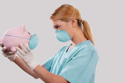 Female doctor wearing a flue mask and holding a piggy bank