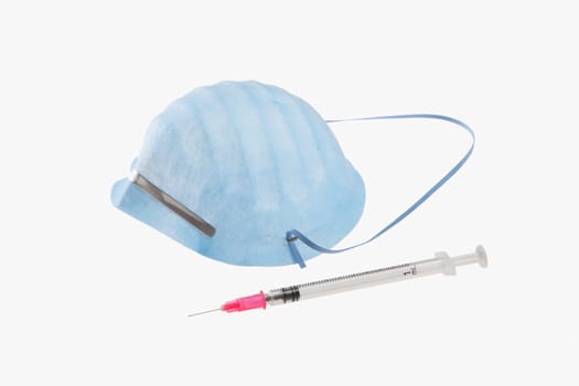 Close_up of a syringe and a swine flu mask