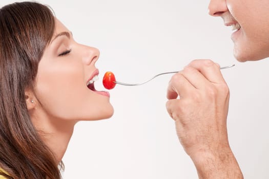Man feeding woman a cherry tomato