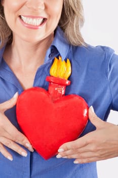 Woman holding an artificial burning heart against her chest and smiling