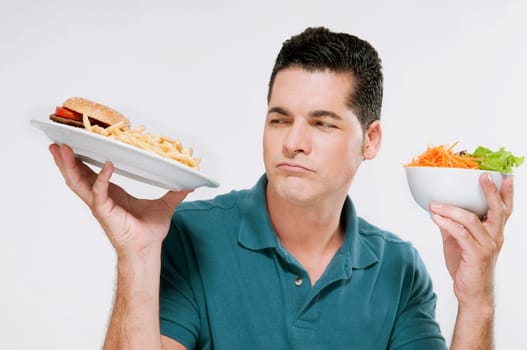 Man choosing between a hamburger plate and a salad bowl