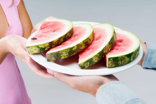 Couple holding a plate of watermelon slices