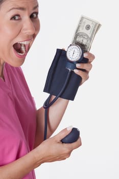Female doctor holding a blood pressure gauge with currency notes