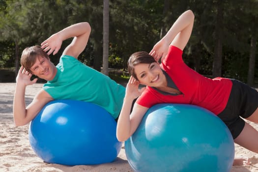 Couple exercising with fitness balls on the beach