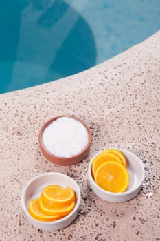 Bowls of orange slices and moisturizer cream at poolside