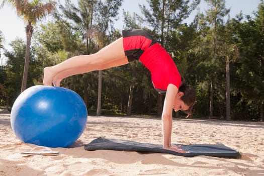 Woman exercising with a fitness ball on the beach