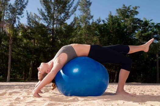 Woman exercising with a fitness ball on the beach