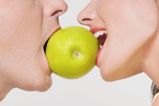 Couple biting into a green apple