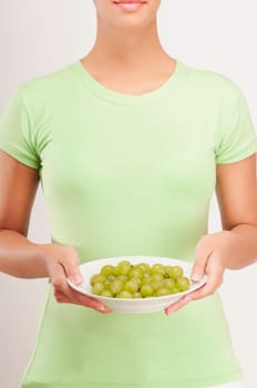 Mid section view of a woman holding a bowl of grapes