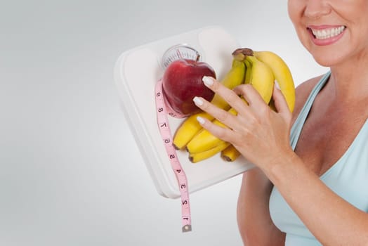Woman holding a bathroom scale and fruits