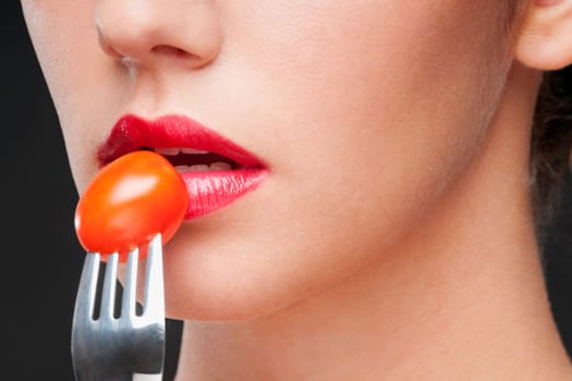 Close_up of a woman eating a cherry tomato