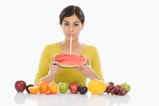 Portrait of a woman drinking from a watermelon with a straw